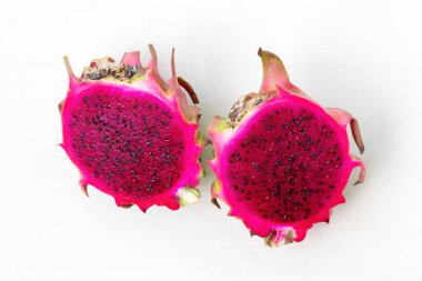 Beyaz arka planda iki parçaya bölünmüş taze kırmızı ejderha meyvesi..