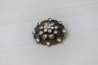 Kadınlar için güzel bir broş, çiçek şeklinde parlak taşlardan yapılmış. Bu mücevher parçası genellikle estetik, kültürel ya da sembolik nedenlerden dolayı bir süs olarak takılır..
