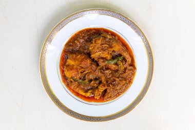 Lezzetli Rui balığı köri ya da Rui mach bhuna beyaz bir tabakta açık ahşap bir yüzeyde. Geleneksel Bengali yemekleri. Üst görünüm.