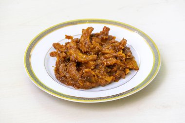 Beyaz bir tabakta servis edilen ev yapımı fil elması turşusu (chalta achar). Bu turşu ekşi, baharatlı ve tatlı bir karışım sunuyor..