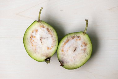 Taze bir guava iki parçaya bölündü. İçinin sulu olduğunu gösteriyor. Guava lezzetli ve sağlıklı bir tropikal meyvedir. Üst görünüm.