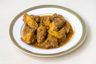 Lezzetli ev yapımı körili tavuk ya da beyaz tabakta tavuk bhuna, açık ahşap bir yüzeye yerleştirilmiş. Otantik Bengali mutfağı pişmiş deshi tavuk eti.