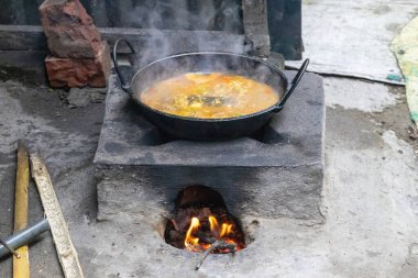 Geleneksel çamur sobasında körili balık pişirme. Bangladeş 'teki köy mutfağı. Bu soba kil ve ahşap ile dolu, kırsal bölgelerde yaşayanlar tarafından kullanılır..