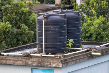 Bangladeş 'te bir evin çatısında siyah plastik su tankları.