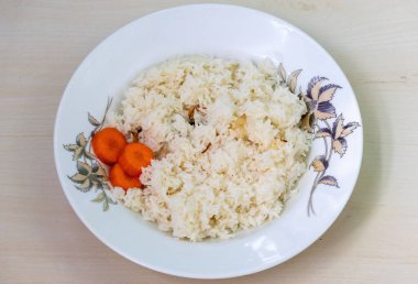 Ev yapımı aromatik pirinç tabağı Polao ya da Pulao, beyaz bir tabakta havuçlu, ahşap bir arka planda. Bangladeş ve Hindistan 'da genellikle koyun eti ya da köri ile servis edilir..