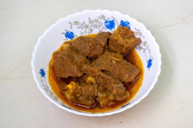 Ahşap arka planda beyaz bir seramik kasede ev yapımı lezzetli bir köri. Beef bhuna popüler, lezzetli ve baharatlı bir Bangladeş yemeğidir..