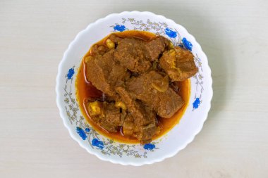 Ahşap arka planda beyaz bir seramik kasede ev yapımı köri. Beef bhuna lezzetli, popüler ve baharatlı bir Bangladeş yemeğidir. Üst görünüm.