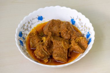 Ahşap arka planda beyaz bir seramik kasede ev yapımı köri. Beef bhuna lezzetli, popüler ve baharatlı bir Bangladeş yemeğidir..