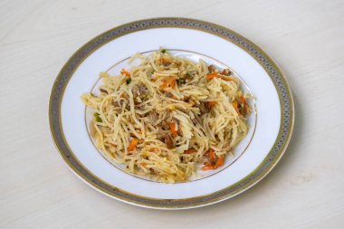 Beyaz seramik tabakta, hafif ahşap bir yüzeye yerleştirilmiş ev yapımı sığır eti çorbası. Biftek, sebze ve tüm dünyada sevilen baharatlı bir yemektir..