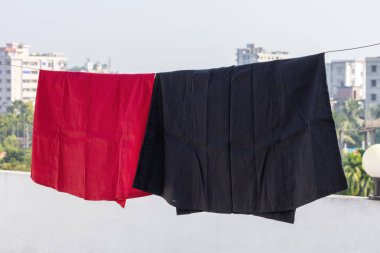 Çatıda çamaşır ipine asılı kırmızı ve siyah bir etek, güneşte kuruyor. Etekler, sarili ya da diğer geleneksel kıyafetlerle kadınların giydiği geleneksel iç çamaşırlarıdır..