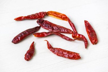 Kurutulmuş kırmızı biber ahşap bir yüzeye saçılmış..