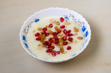 Lezzetli ev yapımı payesh veya payasam, ahşap bir arka planda beyaz bir kasede servis edilir. Süt, şeker, jaggery ve pilavla pişirilir, fındık, kuru üzüm, nar ve fıstık ile süslenir..