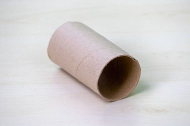 Tek, boş bir tuvalet kağıdı çekirdeği ahşap bir yüzeyde duruyor..