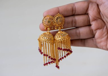 A woman's hand displays a pair of beautiful, vintage, gold-plated earrings. clipart