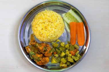 Bhuna khichuri ya da tavuk budu, sebze ve salata ile kızartılmış pirinç, ahşap bir arka planda çelik bir tabakta servis edilir. Üst görünüm.