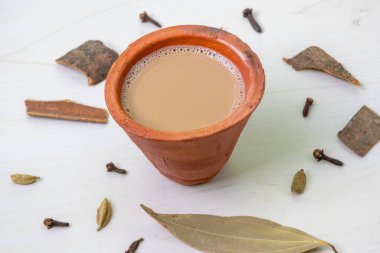 Bir fincan sıcak masala çayı, ya da Hint Kadak Chai, ahşap bir yüzey üzerinde kil bir fincanda servis edilir..