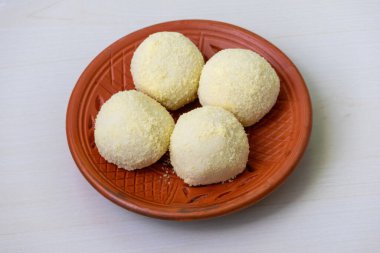 Lezzetli Kachagolla tatlıları ahşap bir zeminde kil tabakta servis edilir. Kanchagolla, yumuşak, süngerimsi dokusu ve ince tatlılığıyla bilinen popüler bir Bengali tatlısıdır..