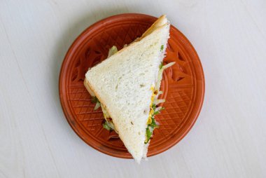 Sağlıklı yumurtalı sandviçin ahşap bir arka planı olan kilden bir tabakta üst görüntüsü..