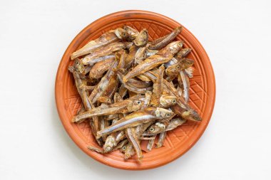 Dried anchovy fish, known as Mola Shutki in Bangladesh, on a clay plate. Top view. clipart