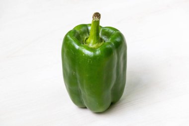 Hafif ahşap bir yüzeyde taze yeşil bir dolma biber. Ayrıca kırmızı biber, biber, biber, biber, kırmızı biber veya kırmızı biber olarak da bilinir..