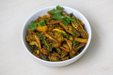 Geleneksel bir Bengali köri balığı olan Mola shutki bhuna, açık ahşap bir yüzey üzerinde beyaz bir kase içinde servis edilir. Lezzetli bir şekilde patates ve brinjal ile pişirilir..