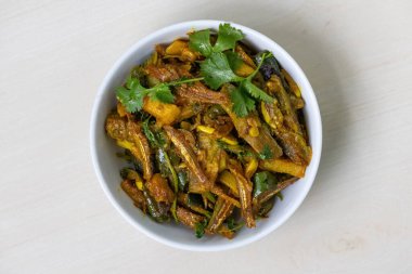 Geleneksel bir Bengali köri balığı olan Mola shutki bhuna, açık ahşap bir yüzey üzerinde beyaz bir kase içinde servis edilir. Patates ve brinjal ile lezzetli bir şekilde pişirilir. Üst görünüm.