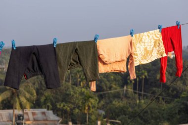 Islak bebek kıyafetleri bir binanın çatısındaki çamaşır ipinde asılı, güneşte ve rüzgarda kuruyor..