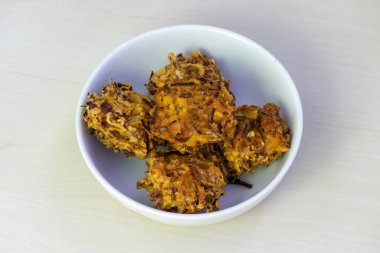 Beyaz bir kâsede servis edilen gevrek, çıtır çıtır pakora. Bu lezzetli kızarmış börekler Bangladeş, Hindistan ve Güney Asya 'nın diğer bölgelerinde popüler bir aperatif ya da aperatiftir..