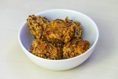 A bowl of crispy pakora, served on a white bowl. These delectable deep-fried fritters are a beloved snack or appetizer throughout Bangladesh, India, and other regions of South Asia. clipart