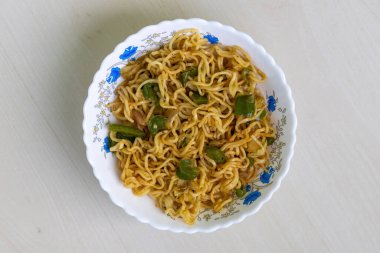 Lezzetli kızarmış şehriye, yeşil dolma biber, domates ve kırmızı biber, beyaz kasede servis edilir. Üst görünüm.