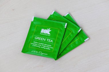 Ahşap arka planda yeşil çay poşeti paketleri.