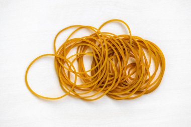 Beyaz arka planda izole edilmiş bir sürü lastik bant var. Kırtasiye, ofis malzemeleri, seyahat, ev eşyaları, tamir ve düzenleme için kalın, elastik bantlar.
