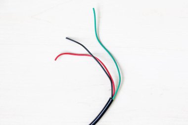 Kullanılan siyah, kırmızı ve yeşil elektrik kabloları, elektronik atıkların geri dönüşümünün önemini vurgulayan beyaz arka planda sergilenmektedir.