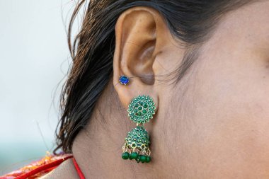 Bengalli güzel bir kadının kulağının yakın çekimi. Hem jhumka küpeler hem de çarpıcı mavi bir küpe ile süslenmiş..