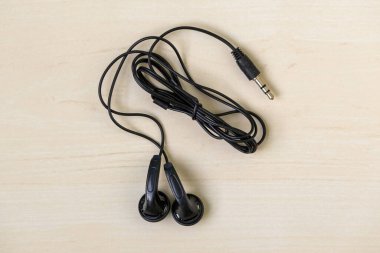 Ahşap arka planda siyah kablo kulaklıklar, üst manzara..