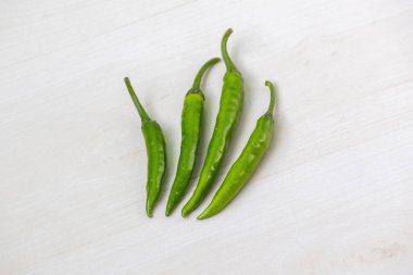 Taze yeşil biber, boyut olarak sıralanmış, hafif ahşap bir yüzey üzerine dizilmiş..