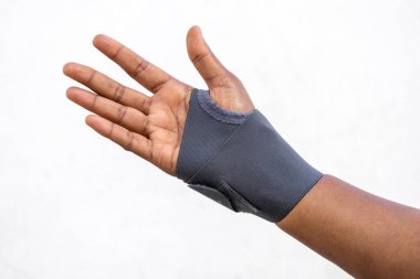 Bilekliği ve başparmağı olan, beyaz bir arka planda izole edilmiş bir kadın eli. Bilek desteği hem sağ hem de sol el için uygun, hem erkekler hem de kadınlar için tasarlanmış..