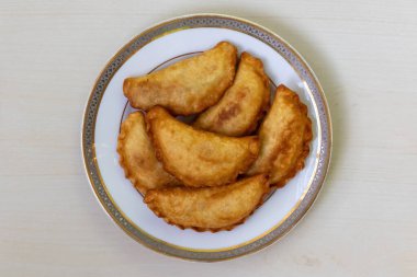 Lezzetli Tavuk Puli Pitha, kızartılmış ve ahşap bir arka planda beyaz bir tabakta servis edilmiş. Bangladeş 'te yaygın olarak kullanılan geleneksel pasta sebze, balık, et, hindistan cevizi ve jaggery dolgusu ile de yapılır.