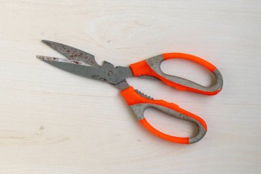 Eski, paslı, turuncu saplı makas tahta arka planda dinleniyordu. Üst görünüm.