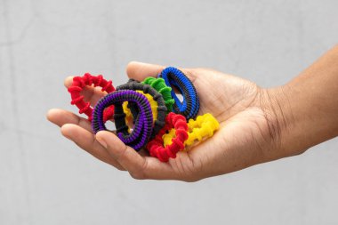 Renkli tokalardan oluşan bir koleksiyonu tutan bir kadın el. Bu kumaş kaplı elastik saç bağları saç bağlamak için kullanılır..