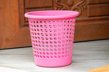 Yerde duran boş bir plastik çöp tenekesi.