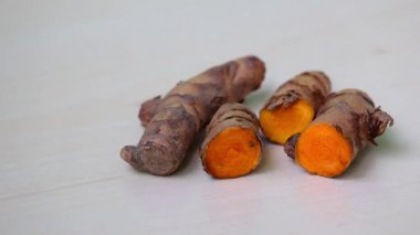 Yakın plan taze, ham zerdeçal, bütün ve ikiye bölünmüş, ahşap bir yüzey üzerinde..