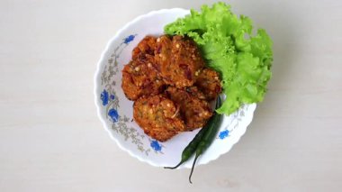 Meşhur bir Müslüman Ramazan atıştırmalığı olan Piyaju adı verilen lezzetli ev yapımı kızarmış mercimek parçaları, açık ahşap arka planda beyaz bir kasede servis ediliyor. Üst görünüm.