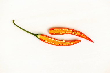 İç dokusunu ve tohumlarını ortaya çıkarmak için ikiye bölünmüş taze kırmızı biber beyaz bir arka planda izole edilir. Acı biberin baharatlı bir tadı vardır ve yemeğe güçlü bir tat katmak için kullanılır..