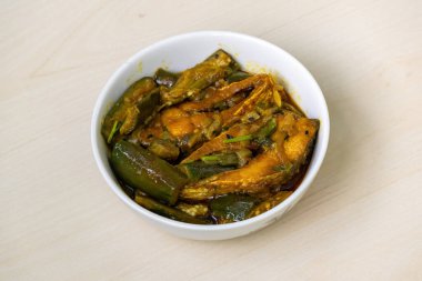 Hilsa balığı (Tenualosa ilisha) ile pişirilen nefis brinjal köri, açık ahşap bir yüzey üzerinde beyaz bir kasede servis edilir..