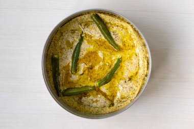 Hafif ahşap bir yüzey üzerinde gümüş çatal bıçakla servis edilen leziz bir kısa dilimleme. Hilsa balığıyla yapılan bu popüler Bengali yemeği hardal tohumlarıyla pişirilir. Üst görünüm.