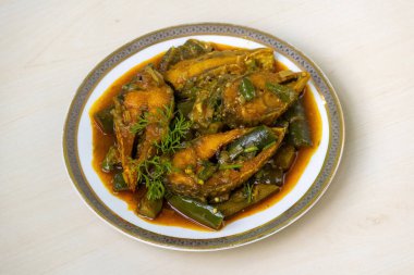 Hafif ahşap bir yüzey üzerinde seramik bir tabakta servis edilen lezzetli brinjal köri Hilsa balığıyla (Tenualosa ilisha) pişirilir. Popüler bir Bengali yemeği..
