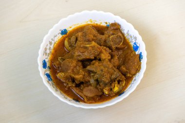 Beyaz bir kâse içinde ahşap bir arka planda nefis bir koyun eti körisi. Koyun bhuna çok lezzetli, baharatlı ve popüler bir Bengali yemeğidir (Bangladeş).