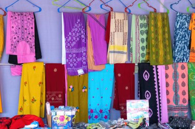 Uluslararası ticaret fuarı Kishoreganj 'da turist satışında askılarda sergilenen kadınlar için üç parçalı renkli pamuklu kumaş. Güzel ceketler ve Salwar Kameez kumaşları..