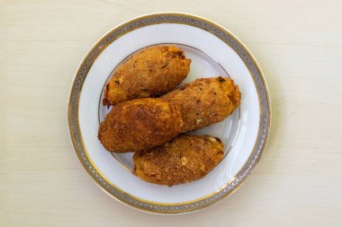 Hafif ahşap bir yüzeyde seramik bir tabakta ev yapımı loş pirzola. Yumurta pirzolası ya da dimer alur pirzolası olarak da bilinen bu lezzetli yemek Bangladeş mutfağında çok popüler bir aperatiftir. Üst görünüm.